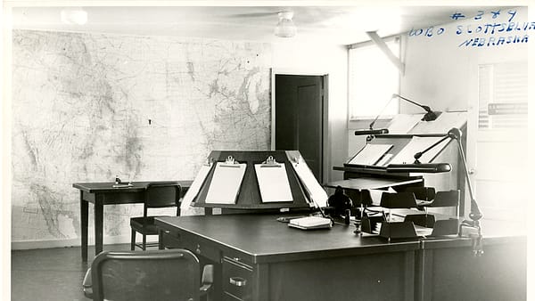 A typed letter on plain paper held flat by a metal ruler on a desk beside a capped pen
