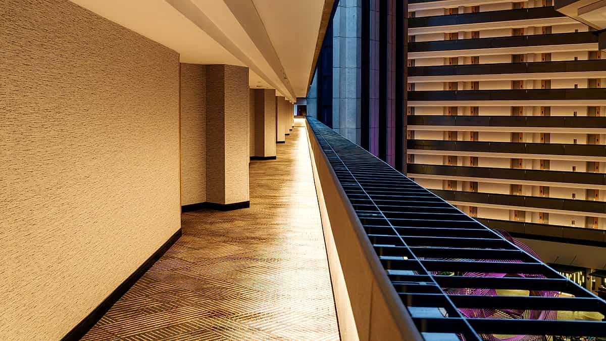 A glass-walled meeting room seen from a corridor, with an empty chair at the head of a long table.